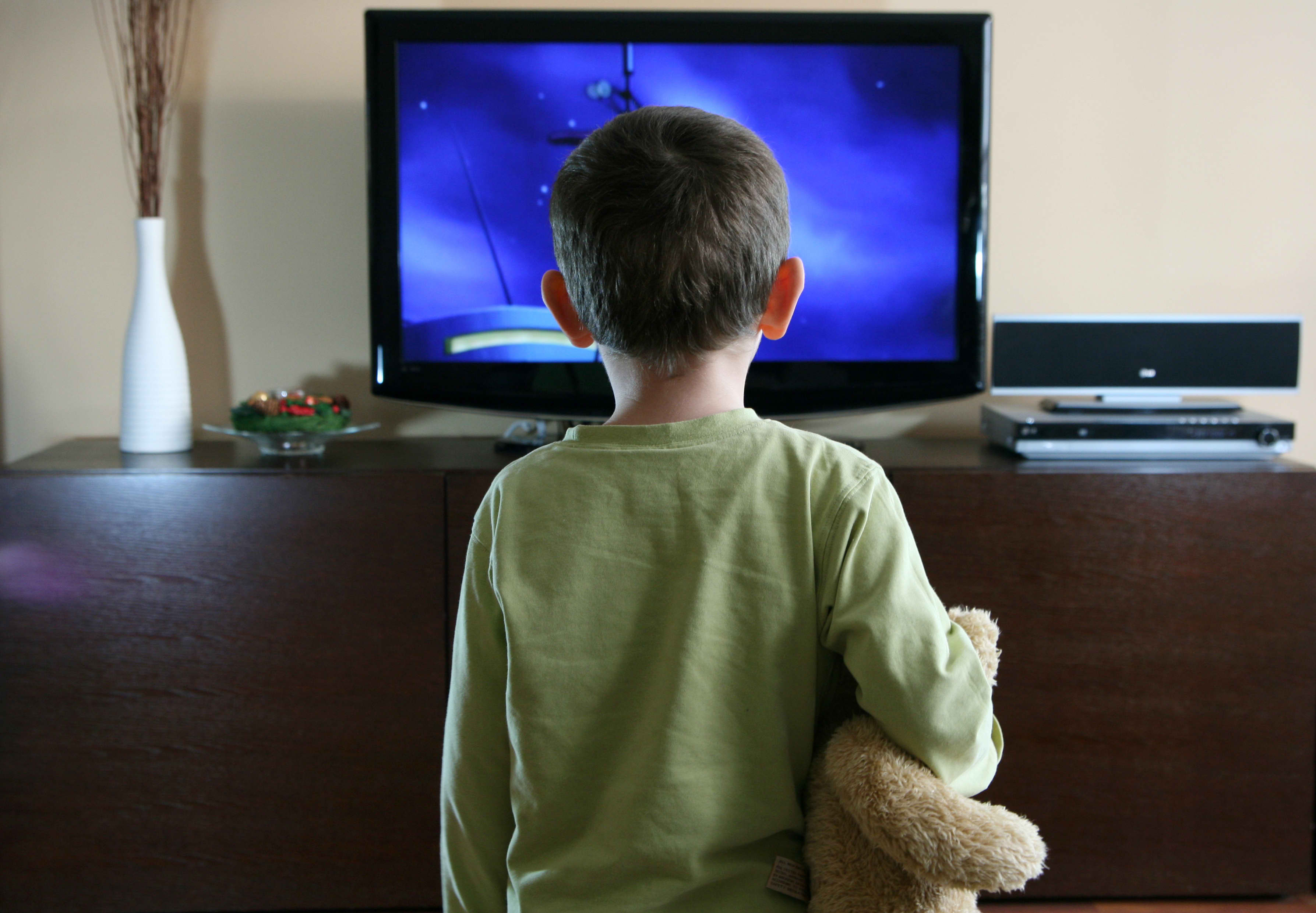 Boy staring at TV with teddy bear