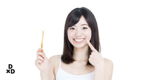 Woman with toothbrush pointing to teeth