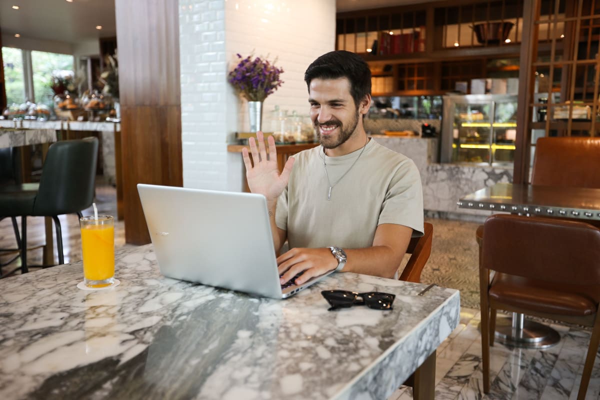 Persona trabajando en un portátil en una cafetería tropical con decoración de plantas exuberantes