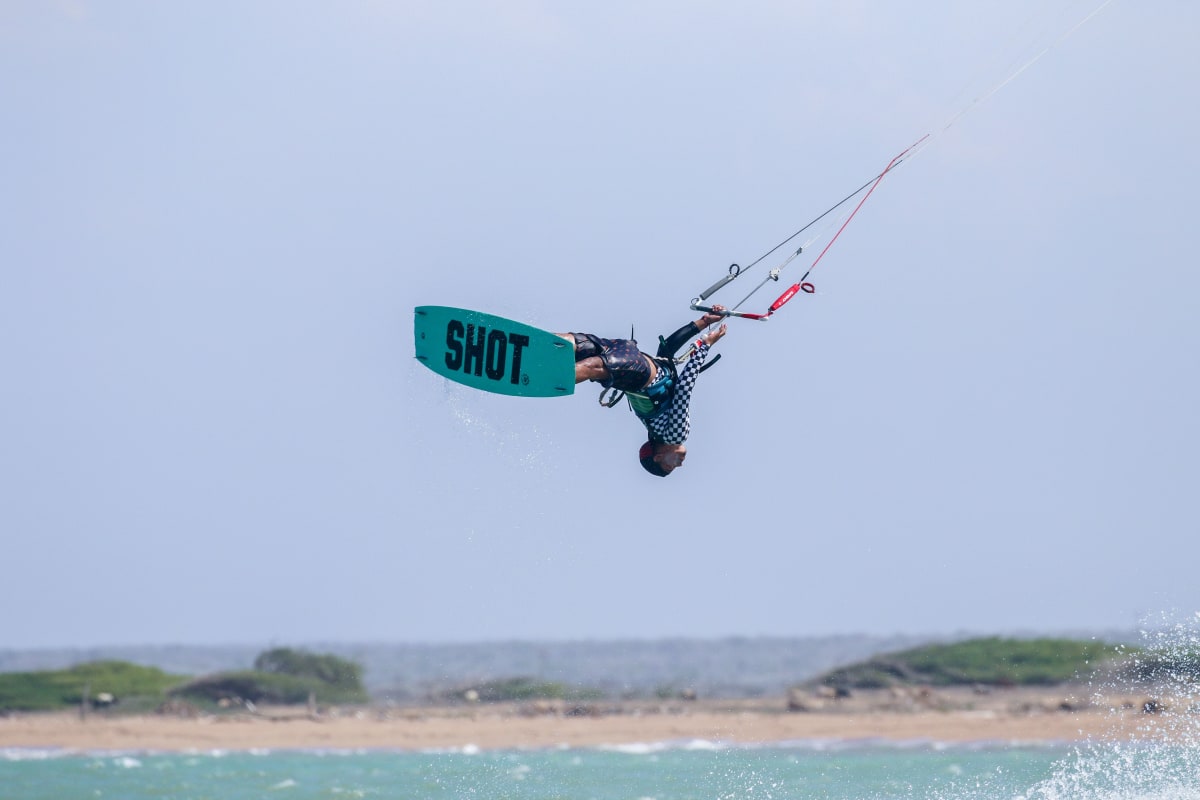 Kitesurfer upside down in mid-air over shallow turquoise water, a reason winter and spring are the best time to visit Holbox for wind