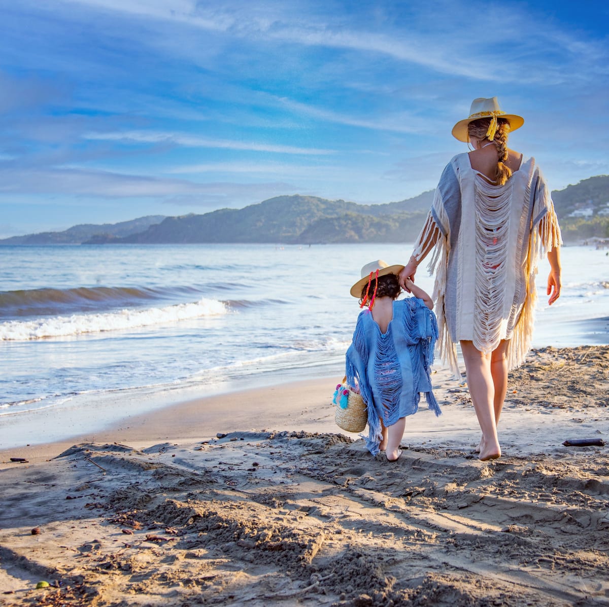 Une mère et sa fille marchent au bord de l’eau sur la plage de Sayulita par une matinée ensoleillée
