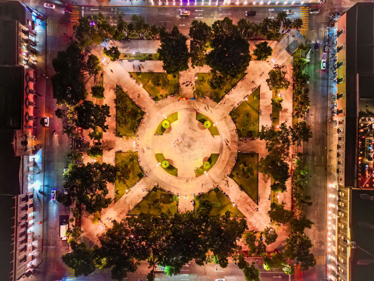 Aerial view of the Plaza Grande in Merida lit up at night with paths and trees, a busy and safe public square