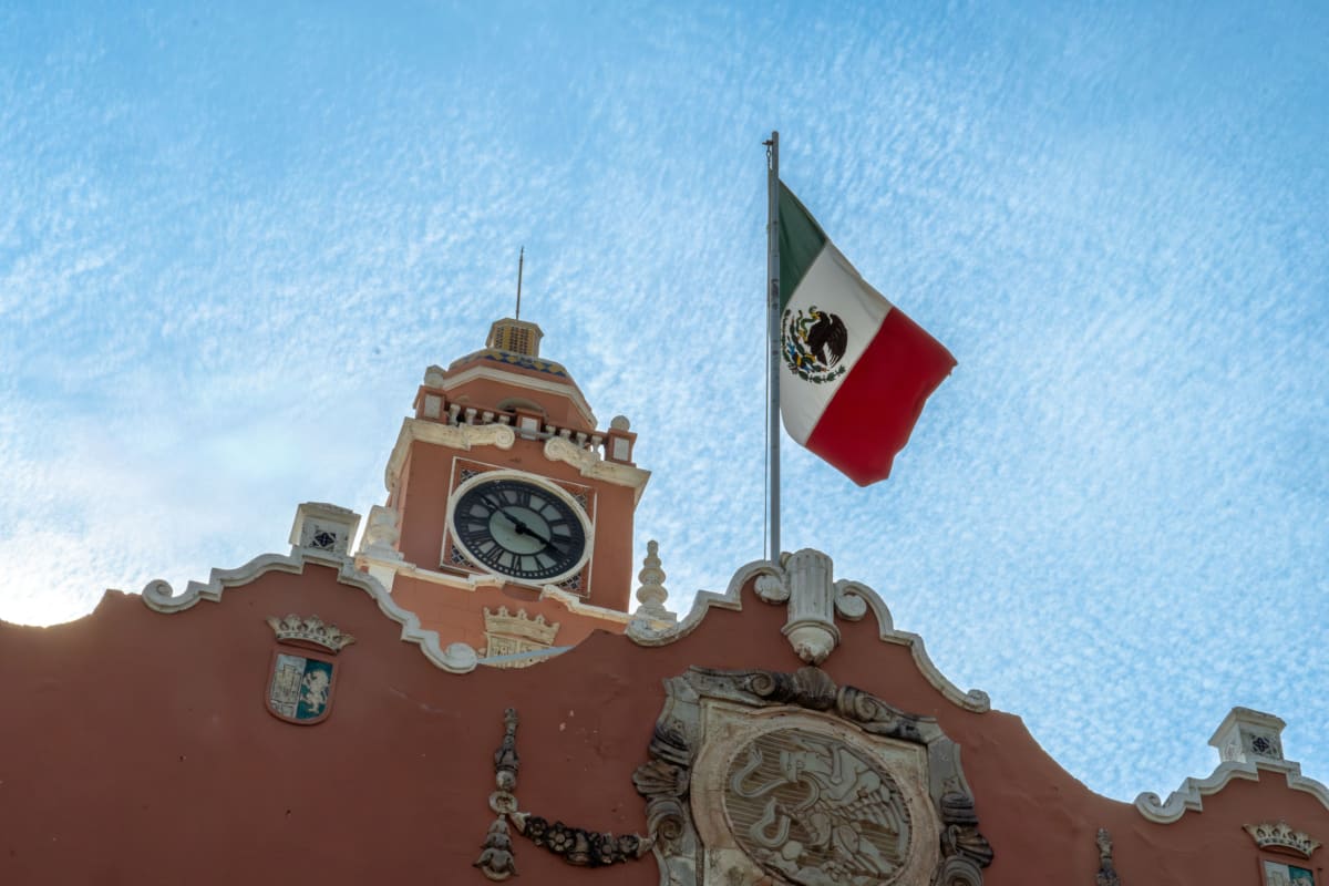 Clock tower of the Merida Municipal Palace with the Mexican flag on the Plaza Grande