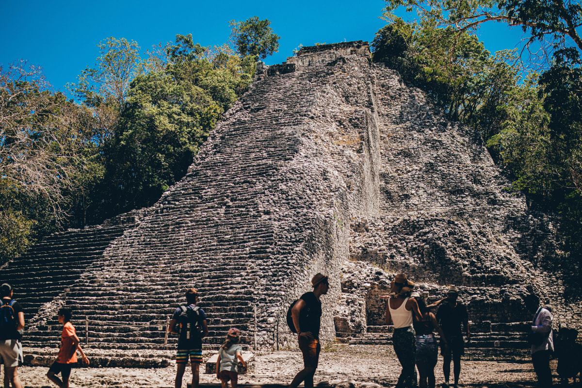 Visitors at the foot of the Nohoch Mul pyramid surrounded by jungle at Coba