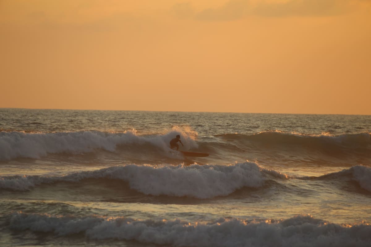 Un surfeur sur une vague au coucher du soleil dans le Pacifique mexicain, le genre de vague visée après des cours de surf à Sayulita