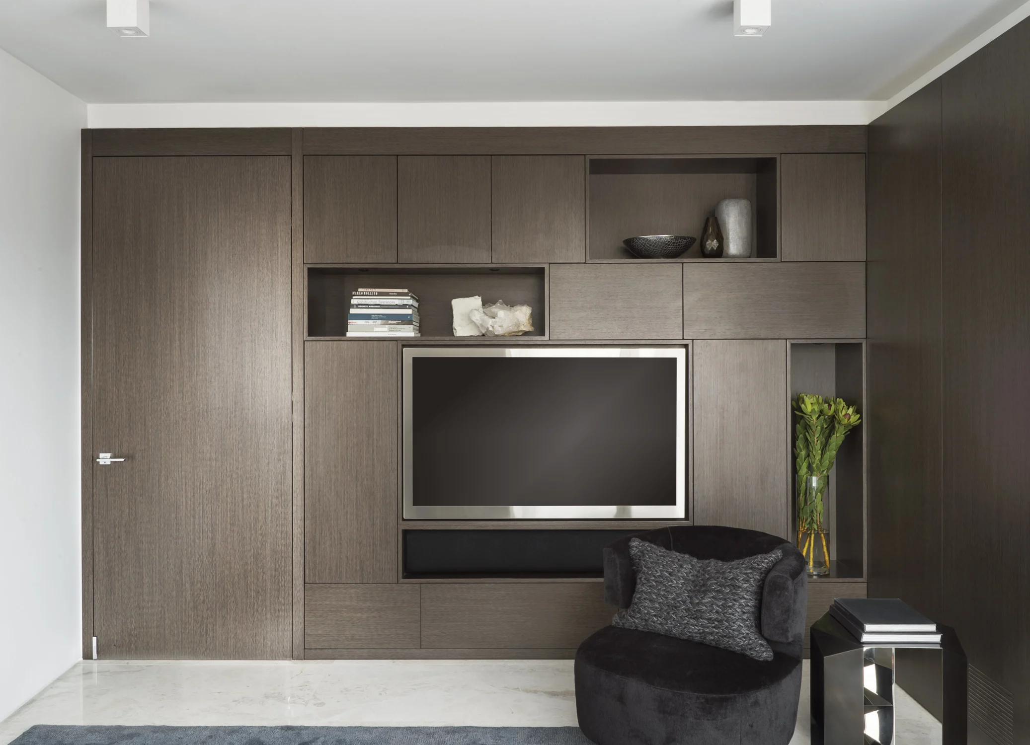 DEN, television, cabinets, built-in cabinets, matte finished side table, stone, black fabric chair, cushion