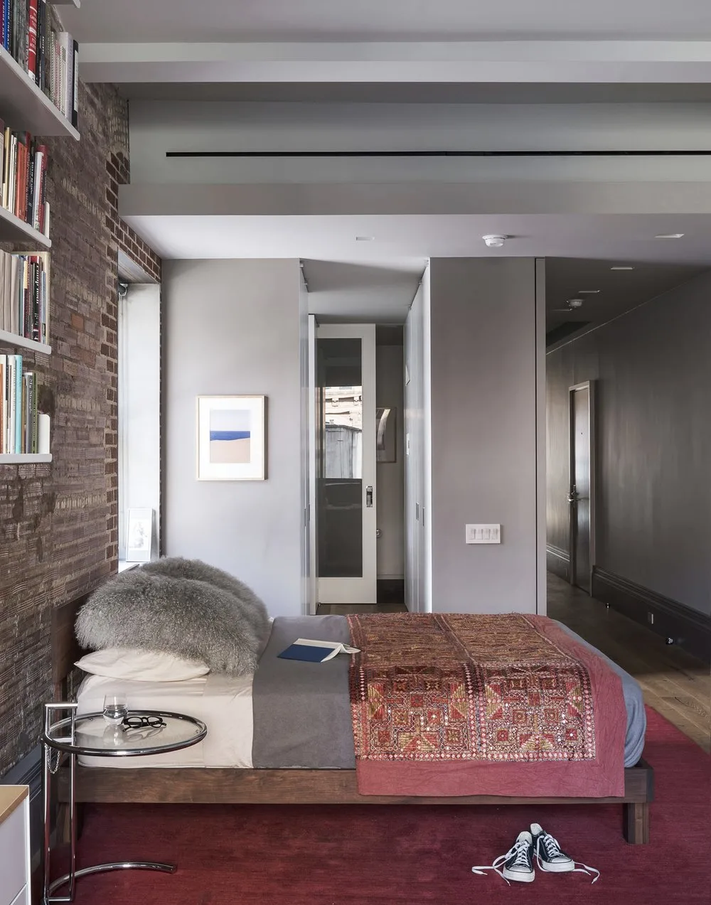 bedroom, brick, bookshelf, rug,pillows,bookshelf, art frame, night stand,shoes, wood