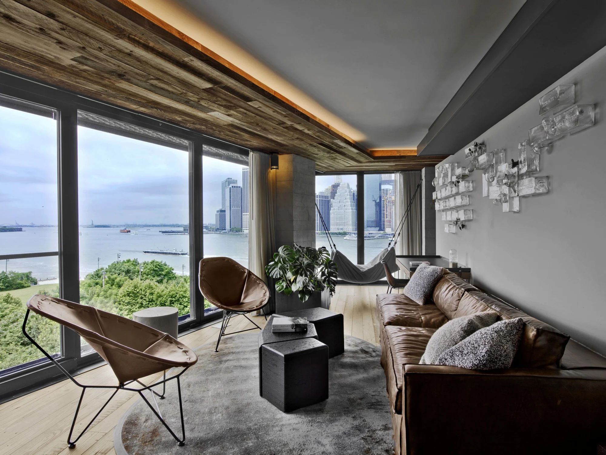Skyline  Leather sofa   chairs  Hammock plant  Accent wall  Coffee tables  Floor-to-ceiling windows  Ceiling light rug