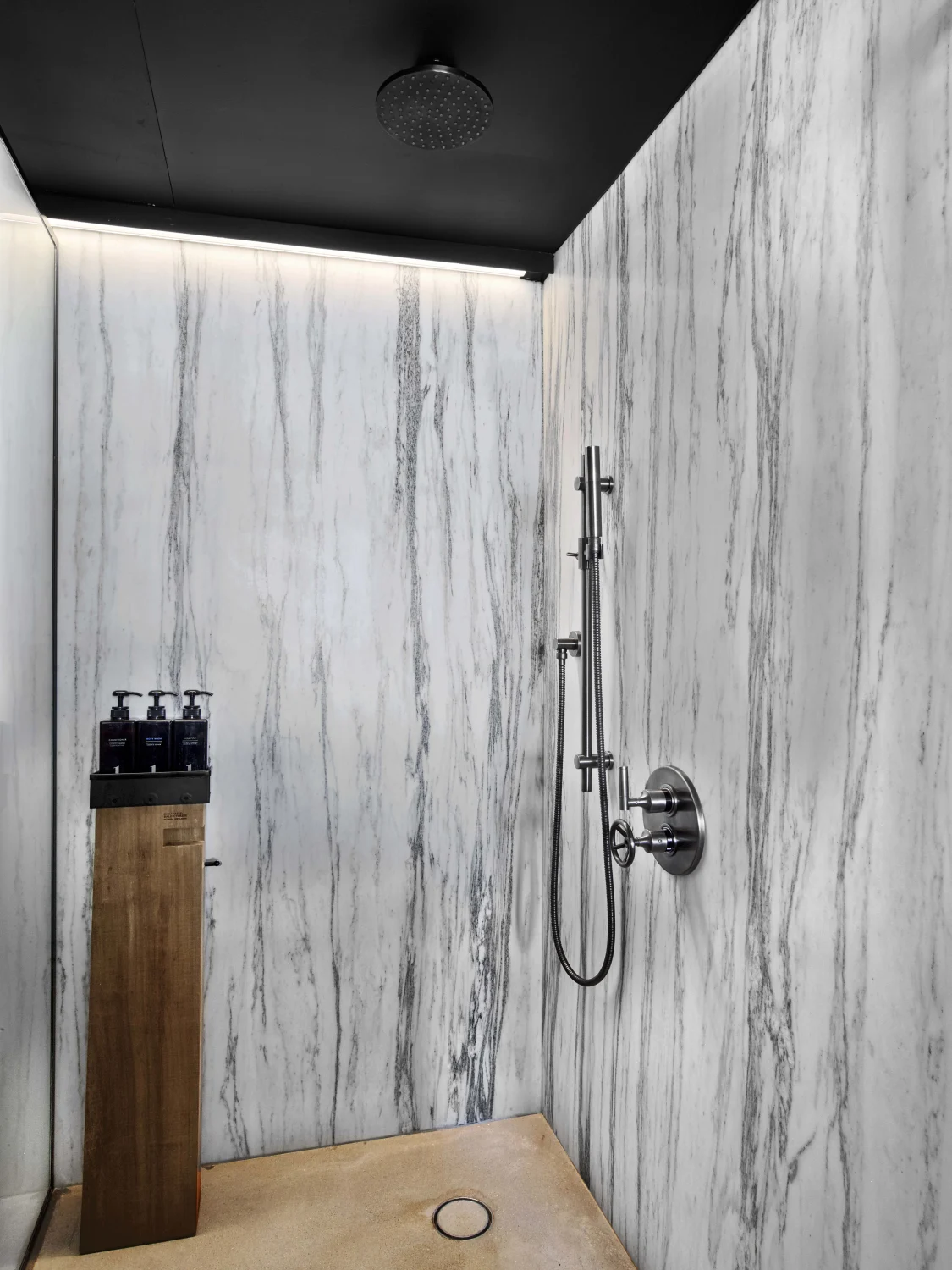 Shower,  Marble walls,  Shower hose,  Ceiling light,  Built-in shelf,  Shower controls , Wooden pedestal , Recessed lighting,  Black ceiling,  Beige floor