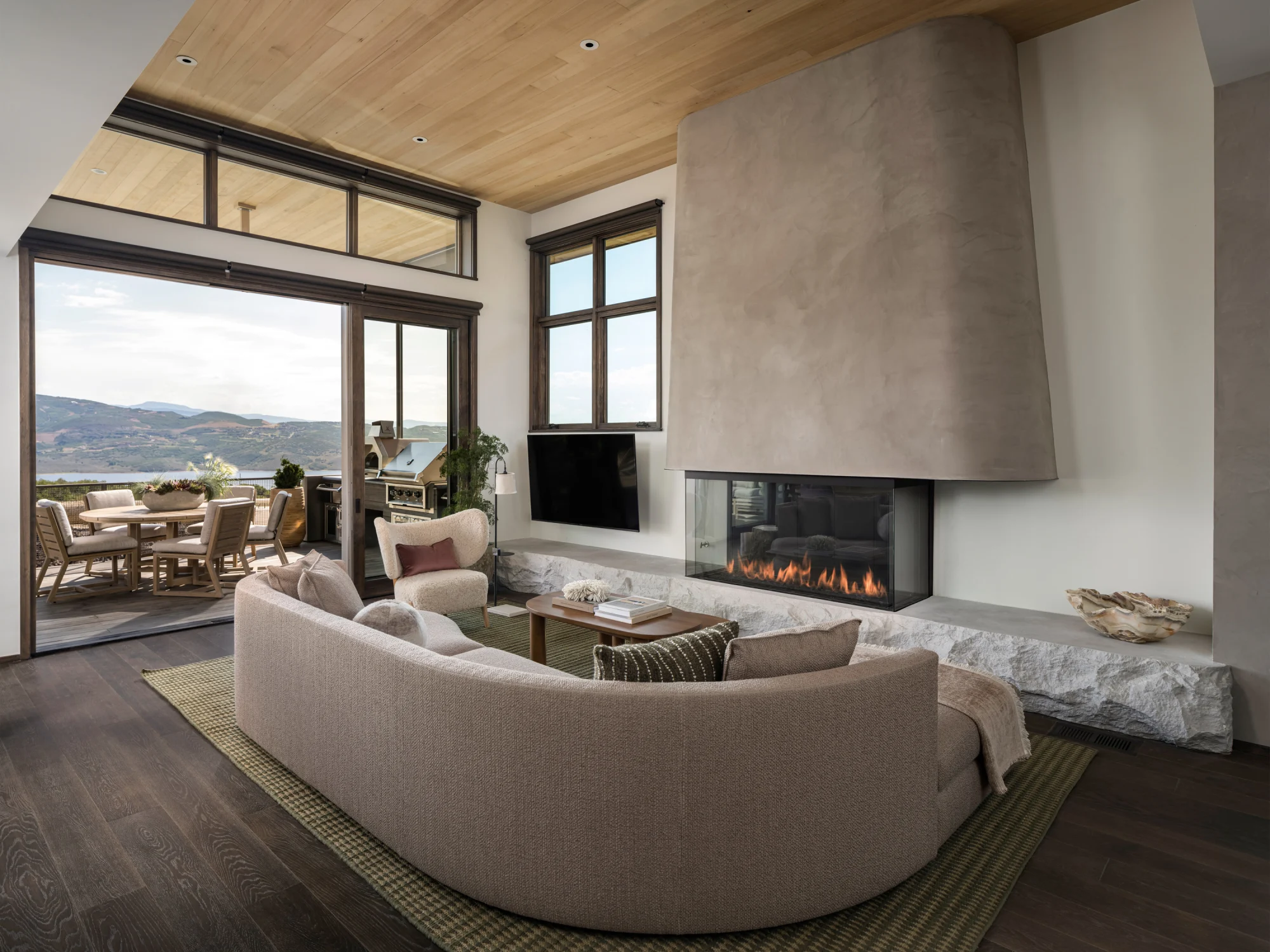 Living room, view, rug, green, fireplace, television, center table, concrete, stone, chair, terrace, windows, couch, wood flooring