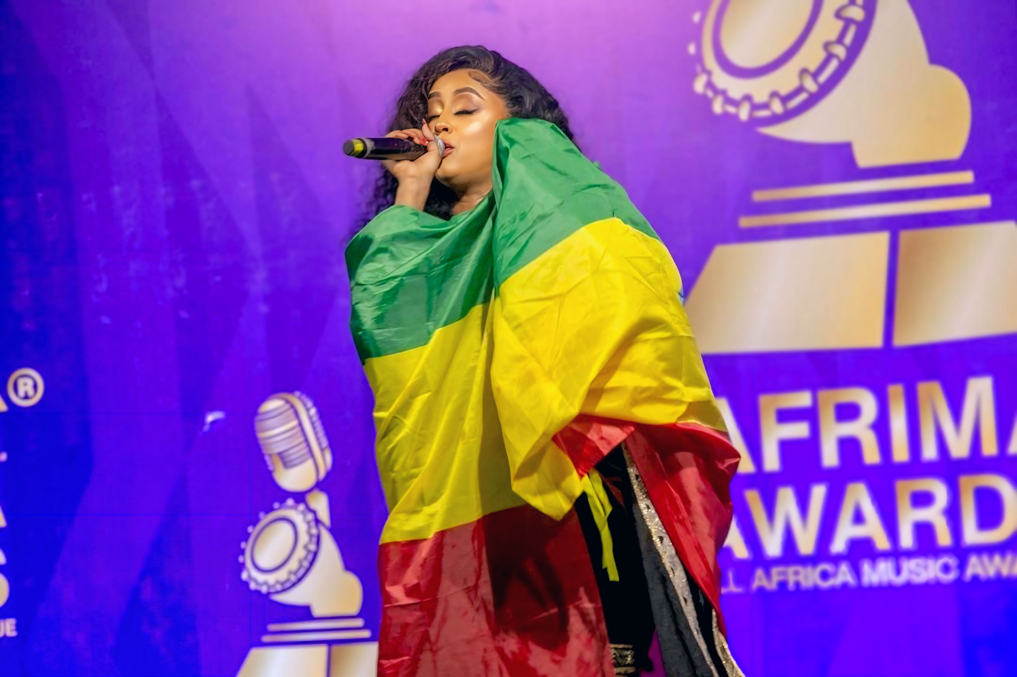 Veronica Adane standing in a black off-shoulder gown against a clean studio backdrop.