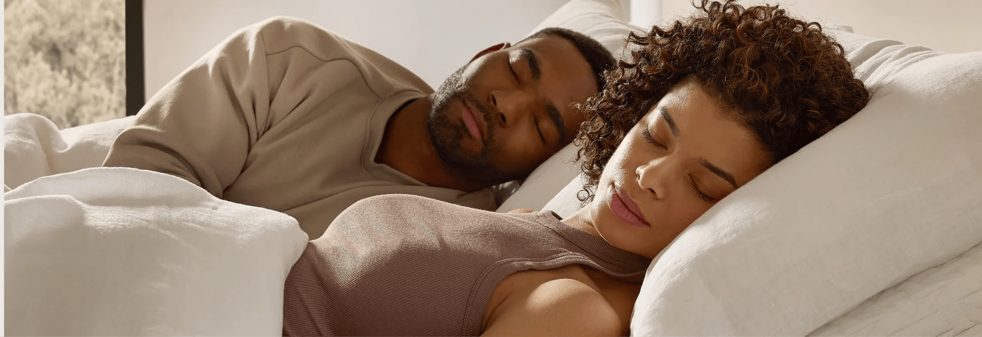 man and woman lying down with their heads elevated on an adjustable base, looking peaceful