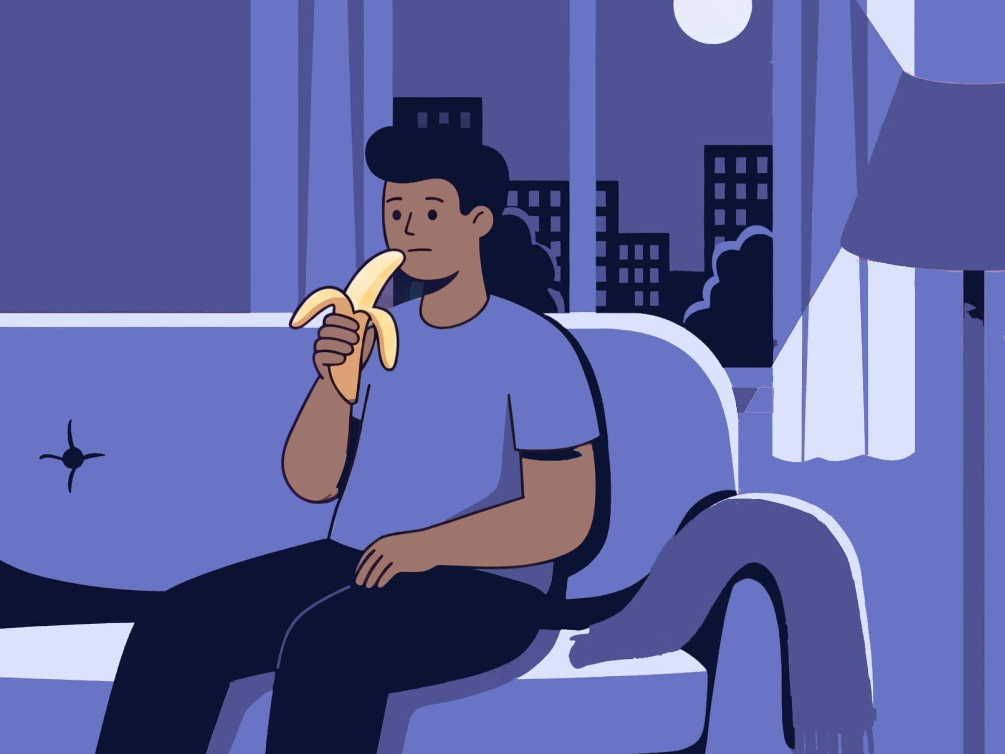 Person on a couch at night, eating a banana, warm low light, casual setting