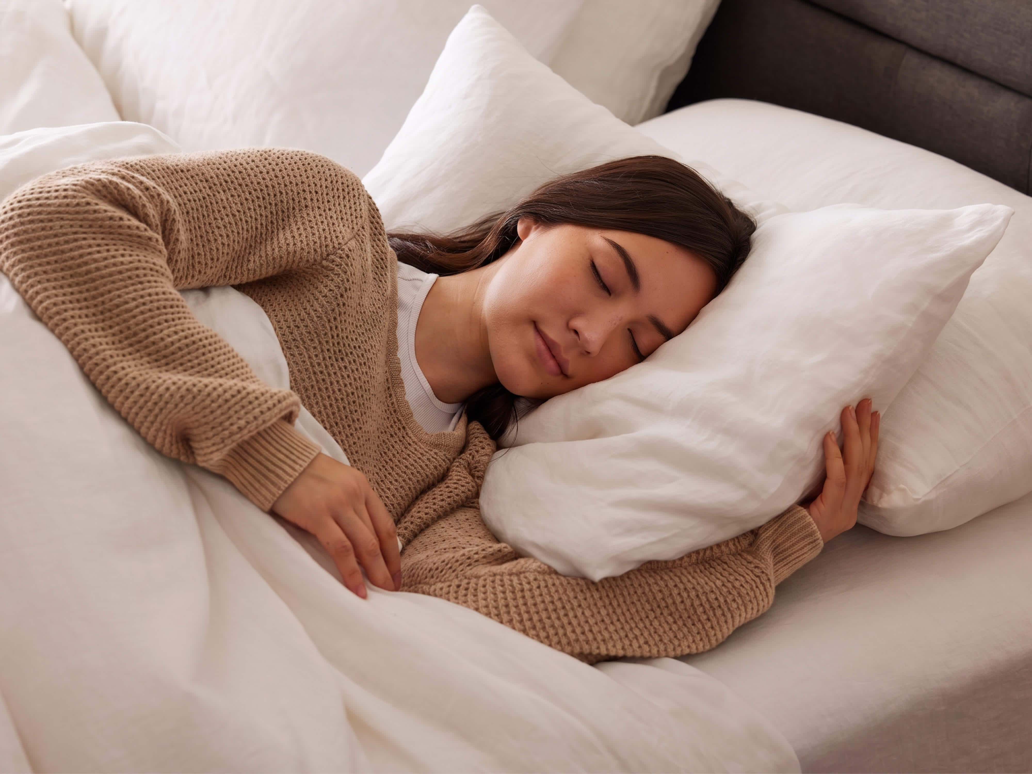 A woman sleeping peacefully on a Chime mattress with white bedding
