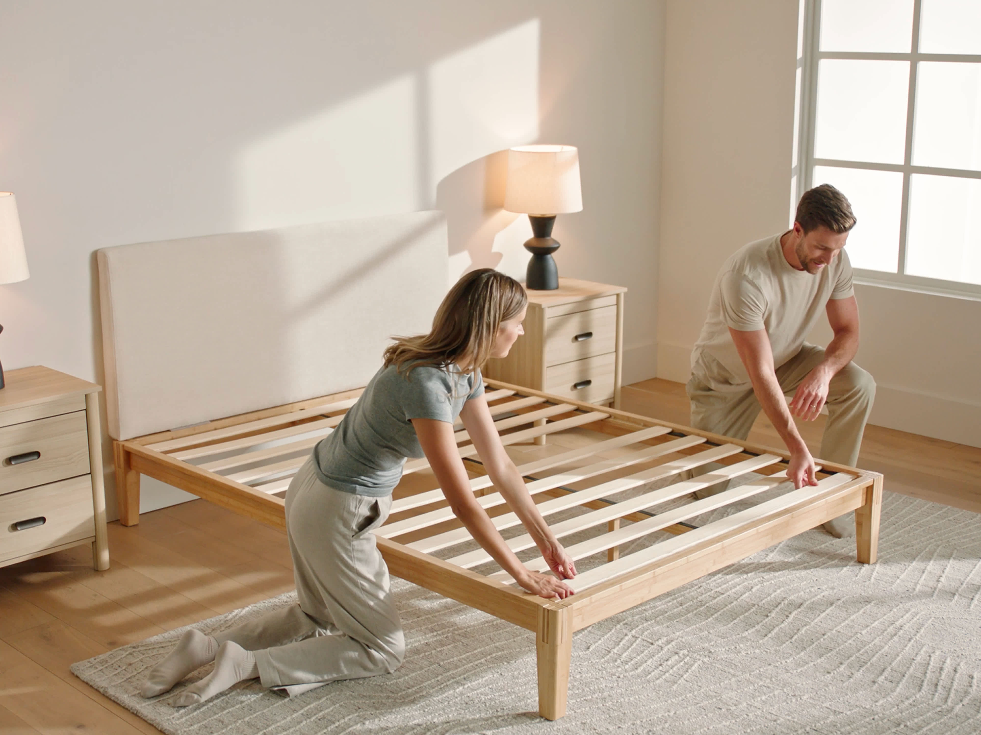 two people assembling a bamboo bed frame