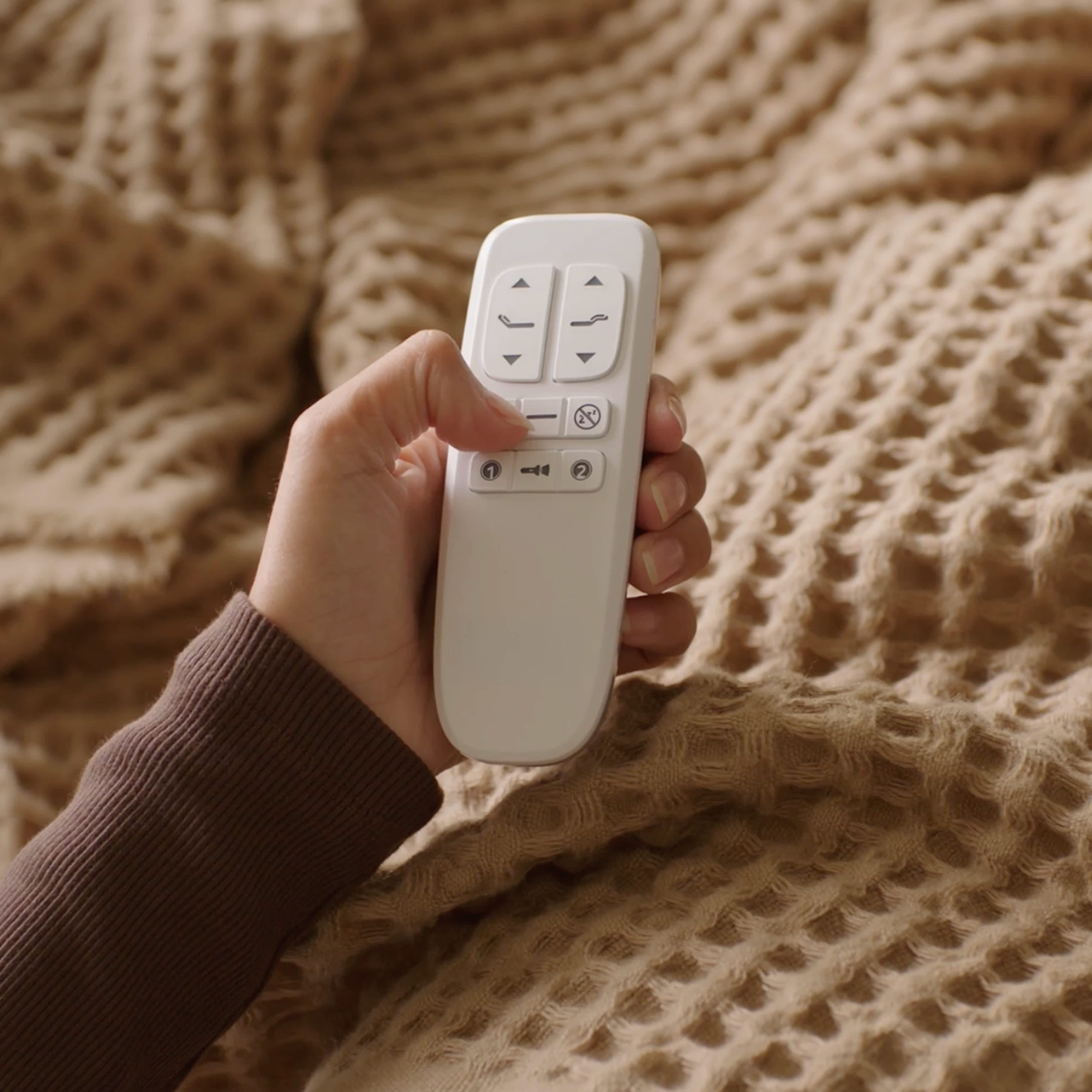 Hand Holding Remote In Bed