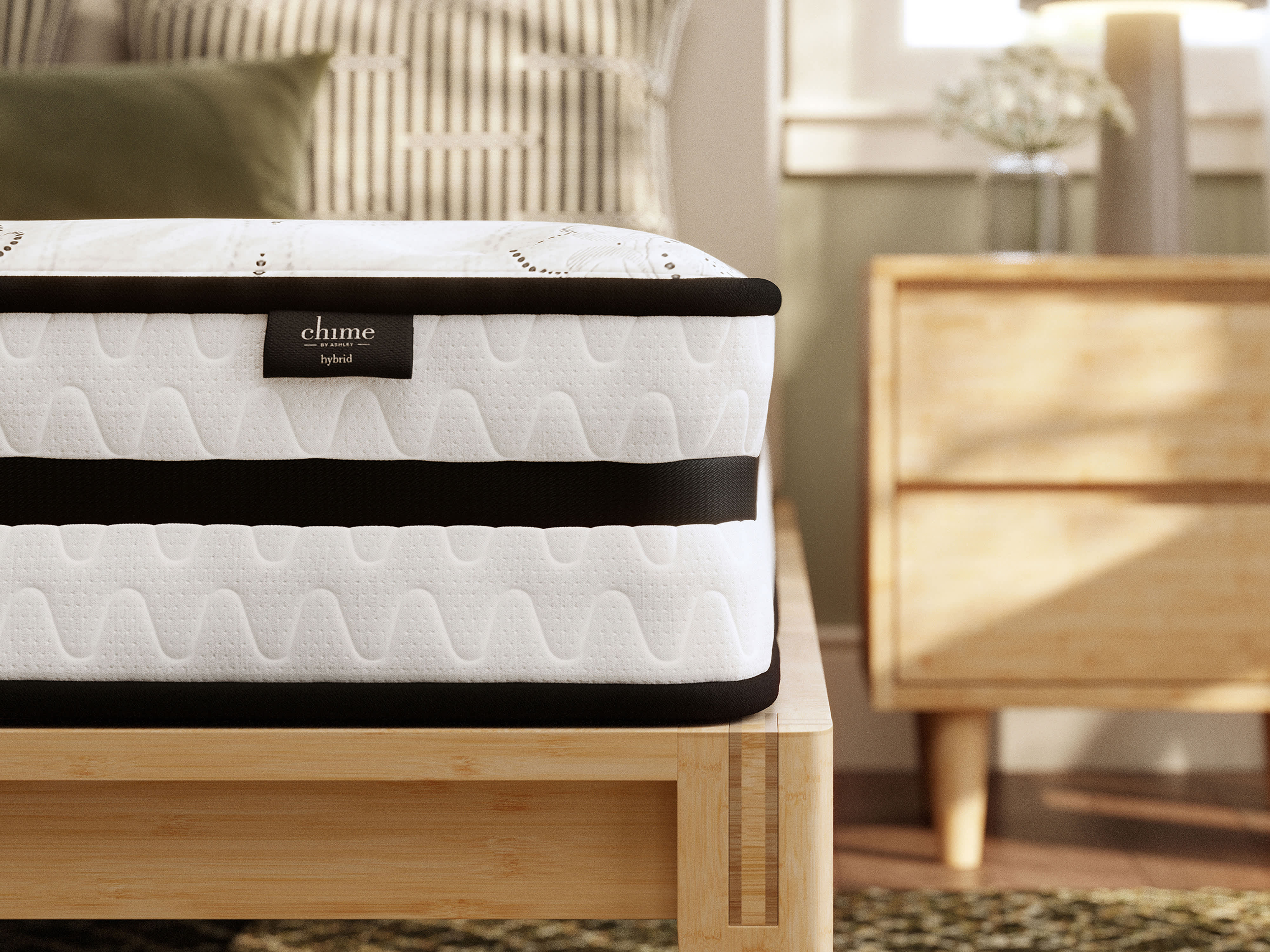 A hybrid mattress with a black and white patterned side on a light wooden bed frame