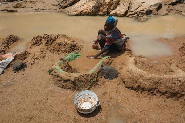 Family team washing ore beneath improvised tarps