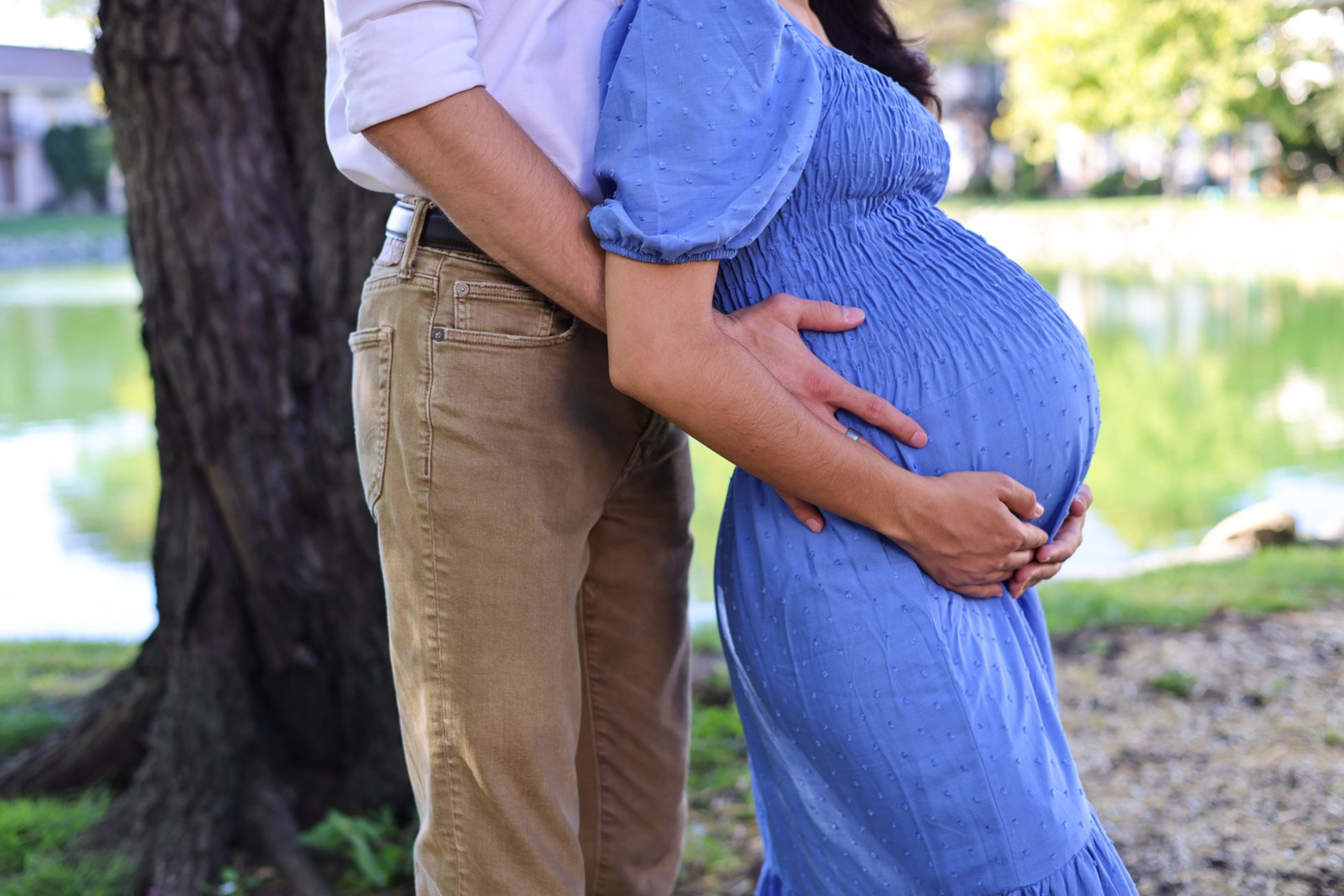 Expecting couple by a garden pond, mom-to-be in a blue gown, southeast Michigan maternity session