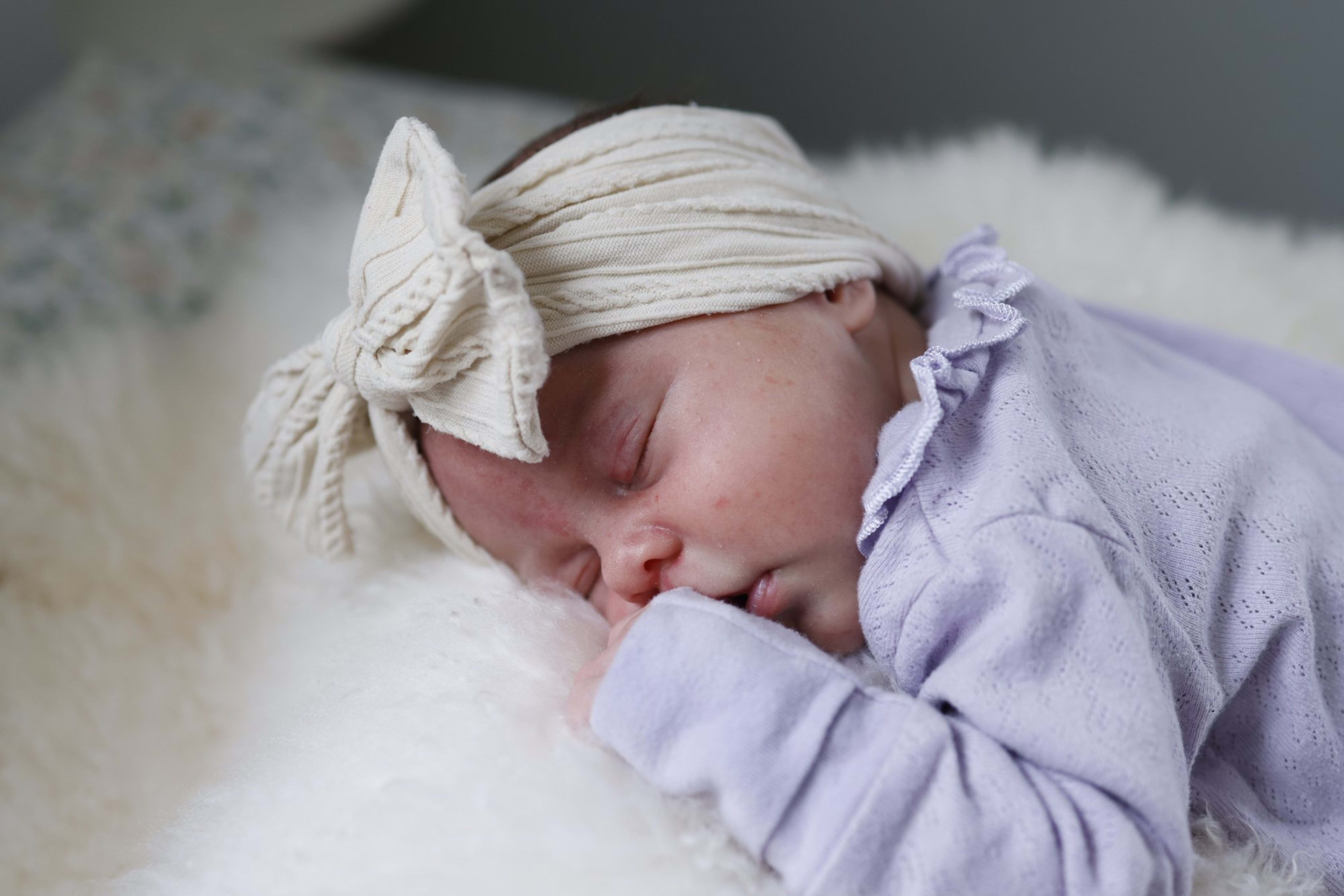 Sleeping newborn girl in lavender with a bow headband, Metro Detroit newborn session