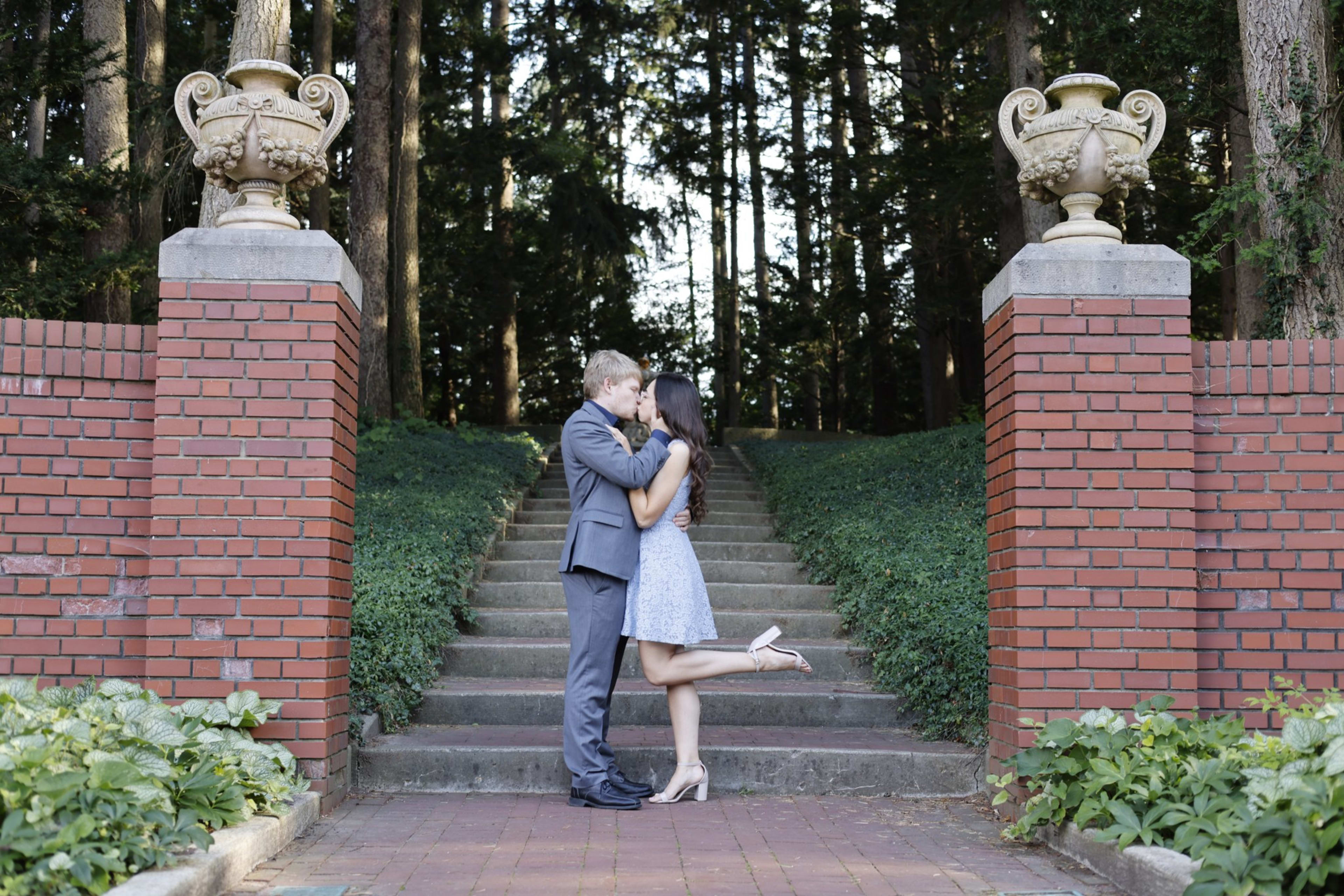 Couple embracing on garden steps framed by brick pillars, Metro Detroit engagement session