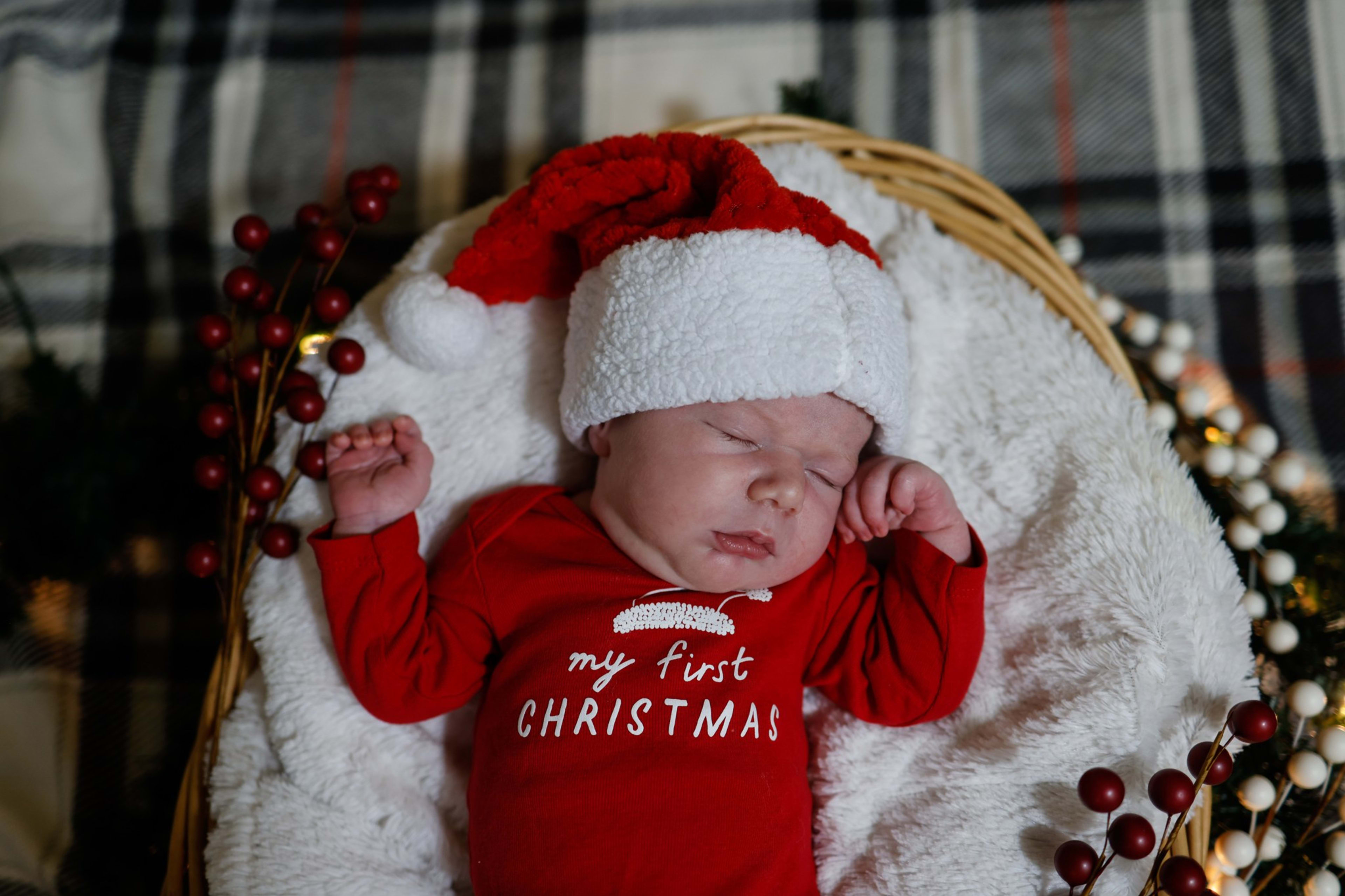 Newborn in a red my-first-Christmas outfit and Santa hat nestled in a festive basket, Metro Detroit newborn session