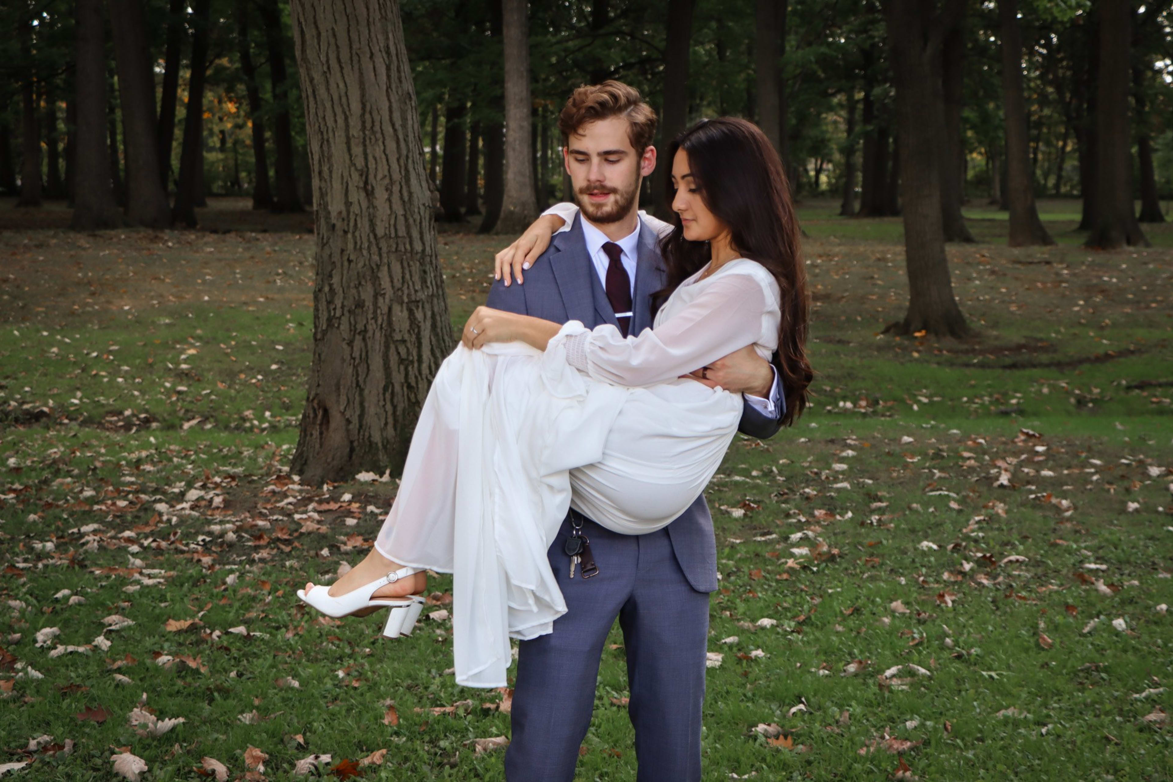 Groom carrying his bride in his arms among the autumn trees, Metro Detroit wedding photography