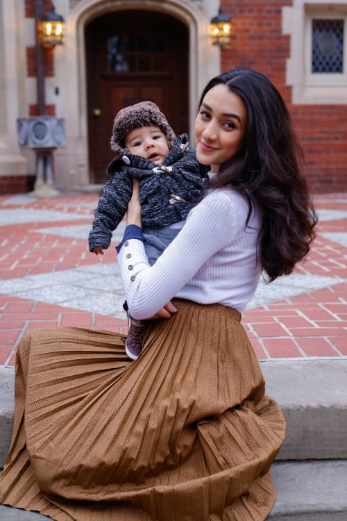 Young woman holding a bundled baby on a brick walkway, Metro Detroit family session