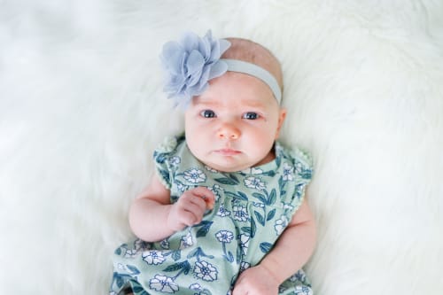 Baby girl in a green floral dress and flower headband on soft fur, Metro Detroit baby session
