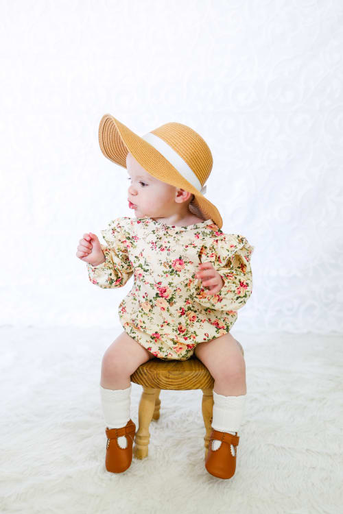 Baby girl in a floral outfit and straw hat on a wooden stool, Metro Detroit sitter session
