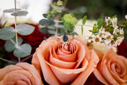 Wedding ring resting on a peach rose with eucalyptus, floral detail shot