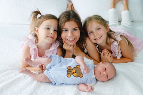 Three sisters gathered around their newborn sibling, Metro Detroit newborn session