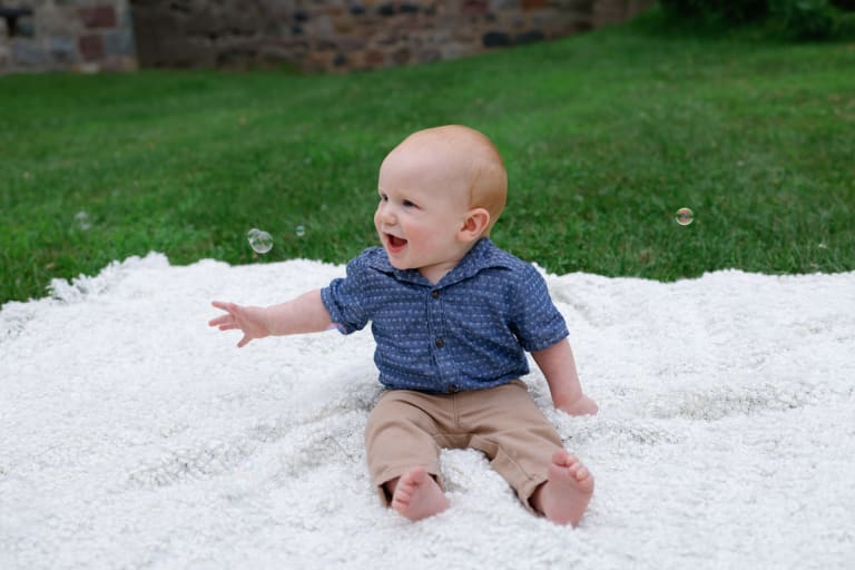 Baby James giggling on a soft blanket as bubbles float past