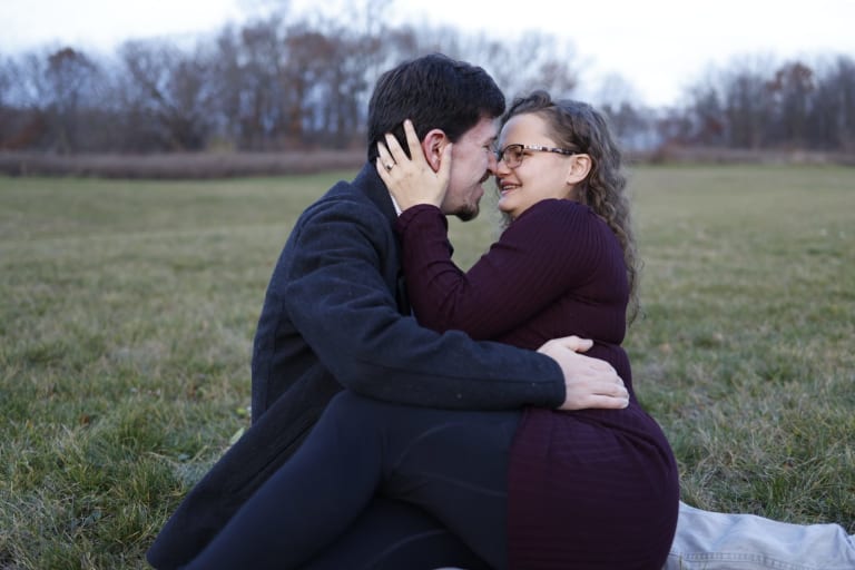 John and Katy sit forehead to forehead in a golden autumn field