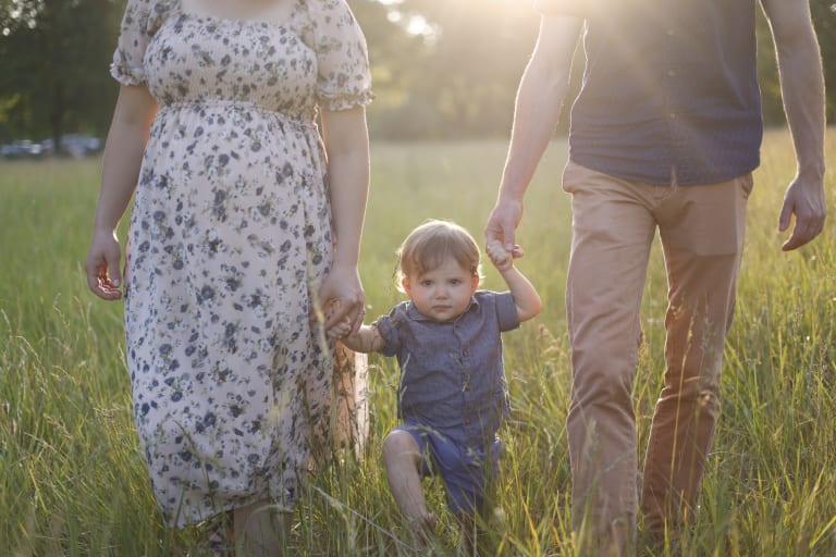 A mother and father walk though a field in Ypsilanti during there family shot 