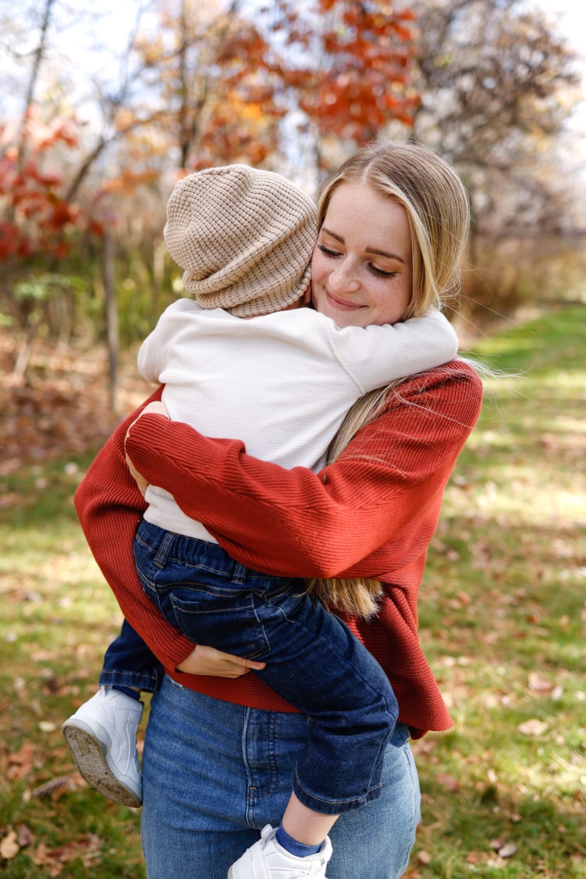 Mother embracing her child in an autumn orchard, southeast Michigan family session