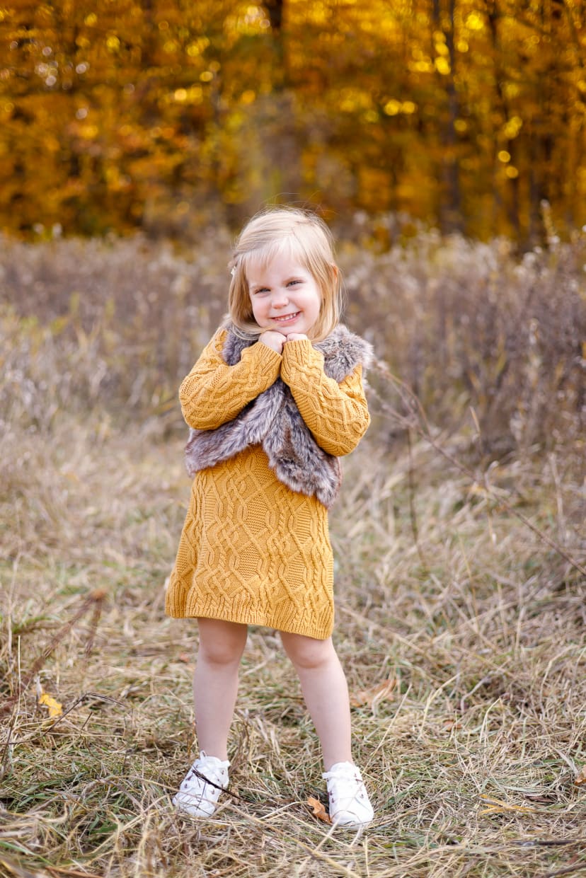 Young girl in a mustard dress standing in an autumn field, southeast Michigan family session