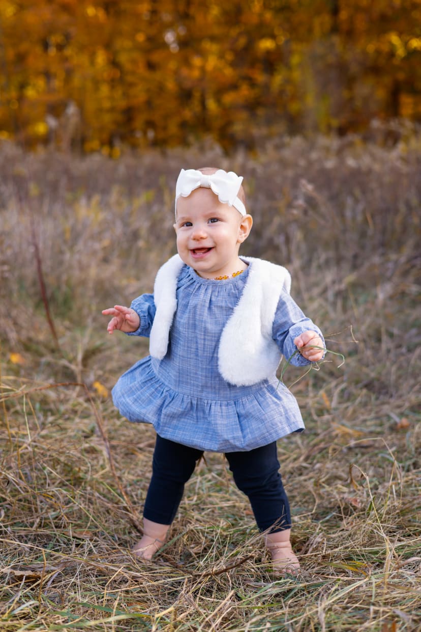 Toddler girl in a blue dress standing in an autumn field, southeast Michigan family session