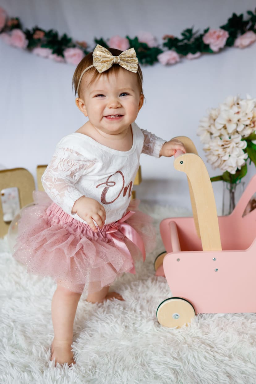 One-year-old girl in a pink tutu with a wooden wagon at her first birthday, Metro Detroit session