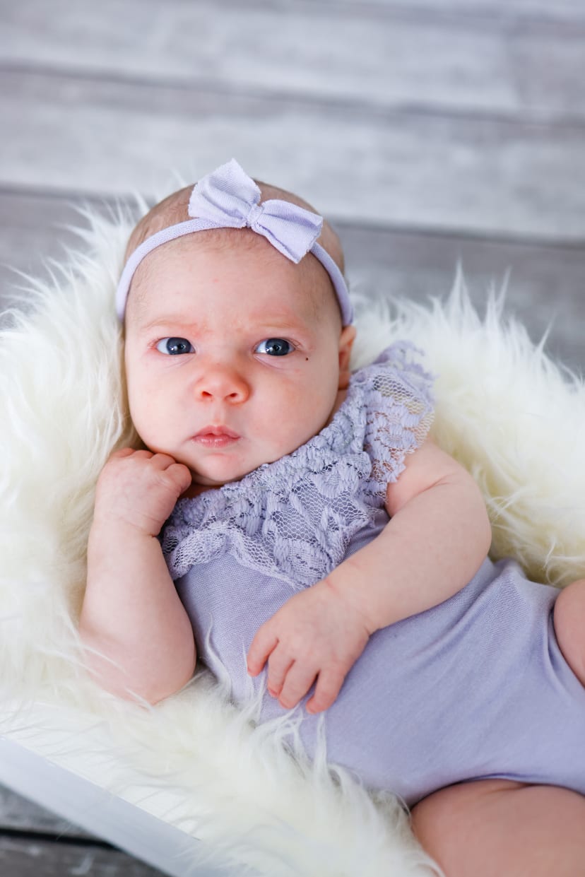 Newborn girl in lace with a white bow on soft fur, Metro Detroit newborn session