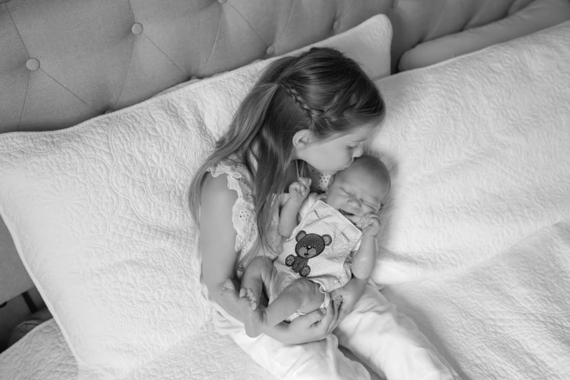 Black-and-white photo of a girl cradling her newborn sibling, Metro Detroit newborn session