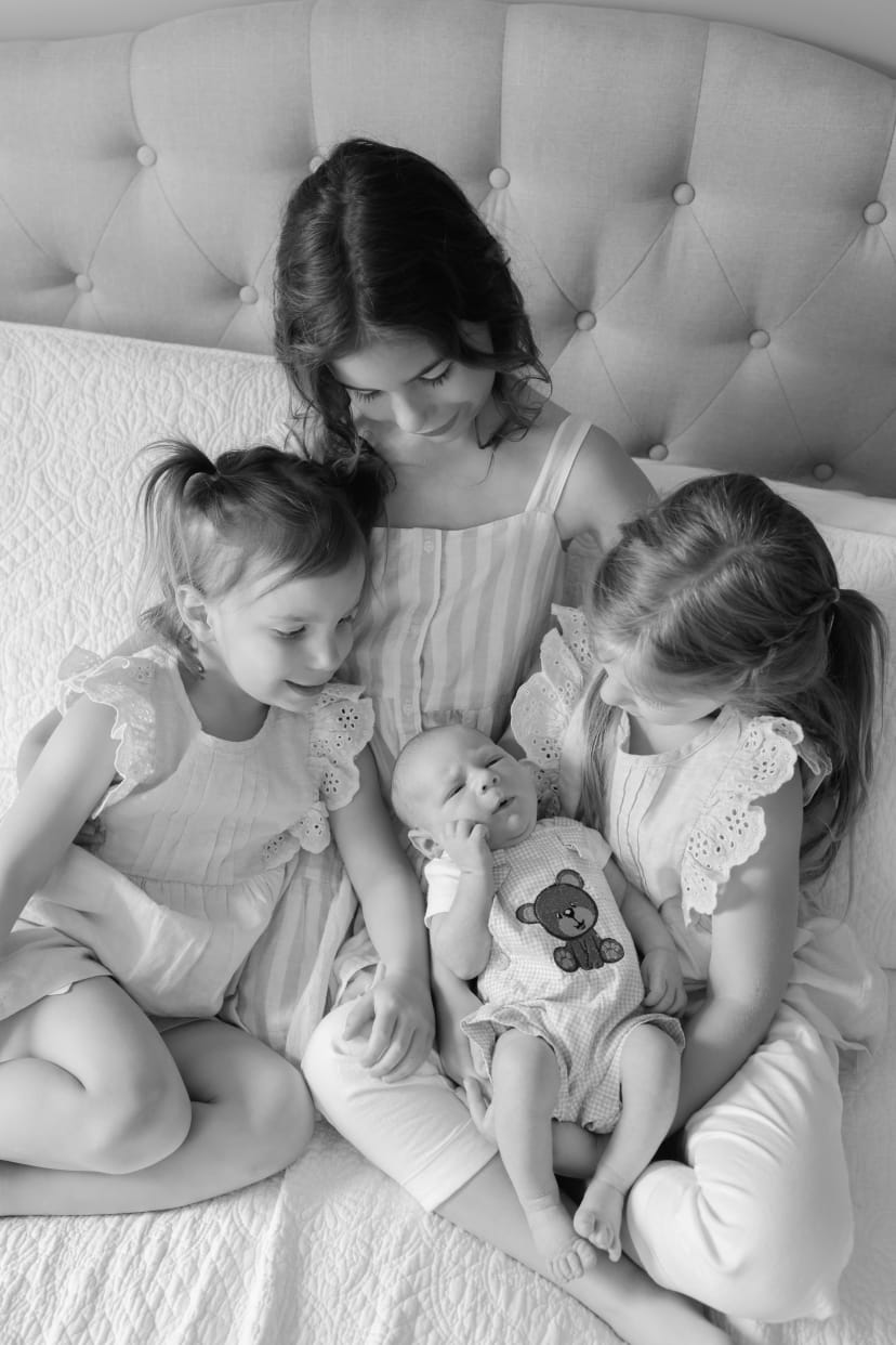 Black-and-white photo of two sisters admiring their newborn sibling, Metro Detroit newborn session