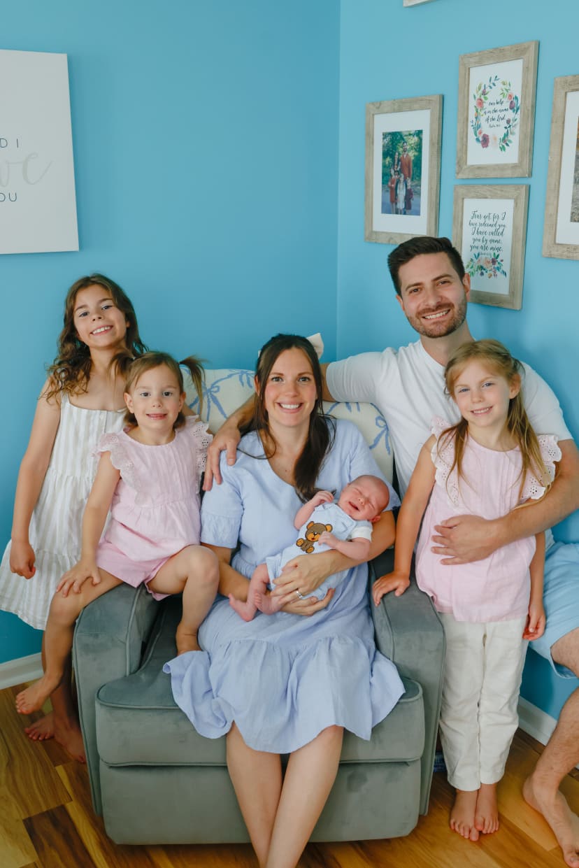 Family portrait with a newborn on a blue-walled couch, Metro Detroit family session