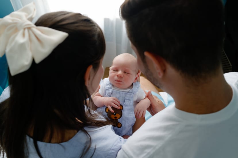 Parents gazing down at their newborn son held between them, Metro Detroit newborn session