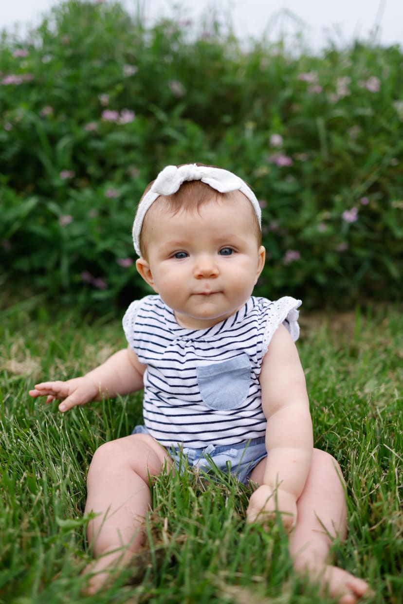 Baby girl in a striped romper sitting in the grass, Metro Detroit outdoor session