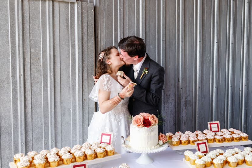 Bride and groom kissing over their wedding cake and cupcakes, Metro Detroit wedding