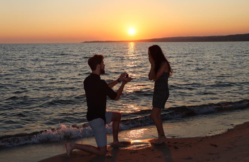 Silhouetted beach proposal at sunset by the water, Michigan lakeshore engagement