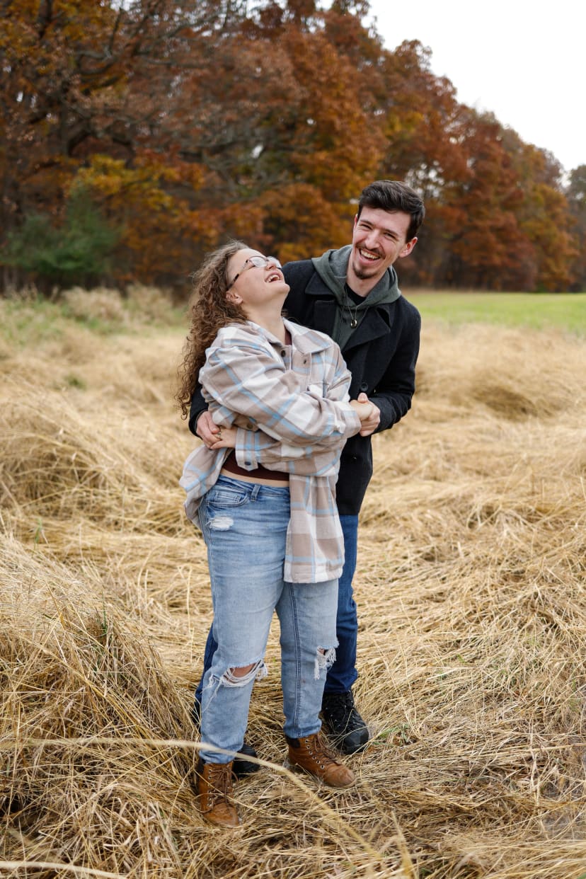 Couple embracing in a golden field at dusk, southeast Michigan engagement