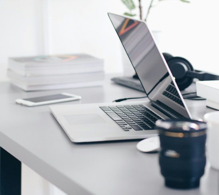 silver MacBook Pro on white table