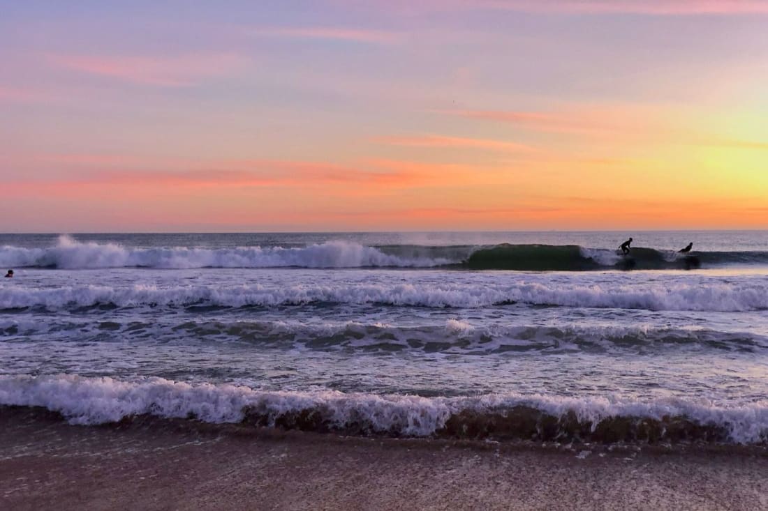 Surfers heading out at sunset on Praia de Carcavelos near Lisbon